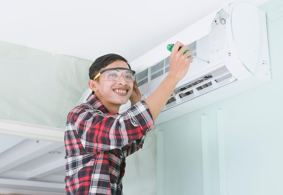 Technician servicing a wall-mounted air conditioner (Florida AC contractor insurance)