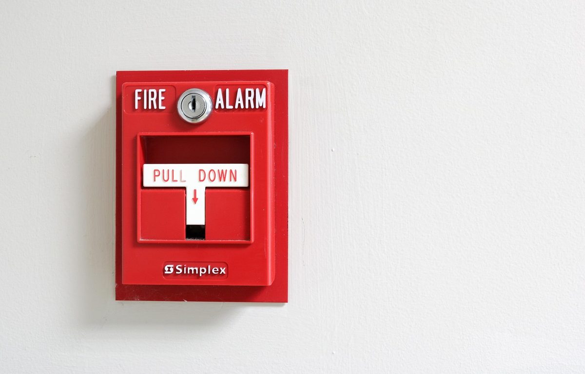 Red fire alarm pull station on a white wall (Florida alarm contractor insurance)