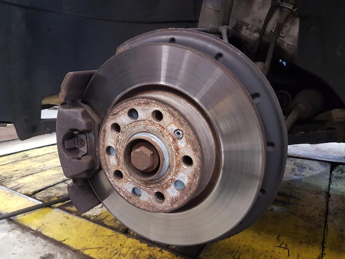 Brake rotor and caliper on a car lifted in a repair shop (Florida auto repair insurance)