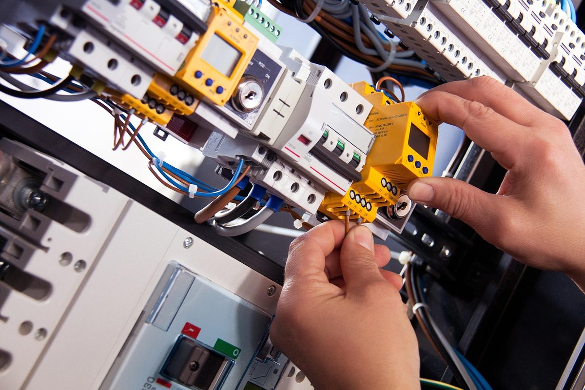 Electrician wiring circuit breakers in an electrical panel (Florida electrician insurance)