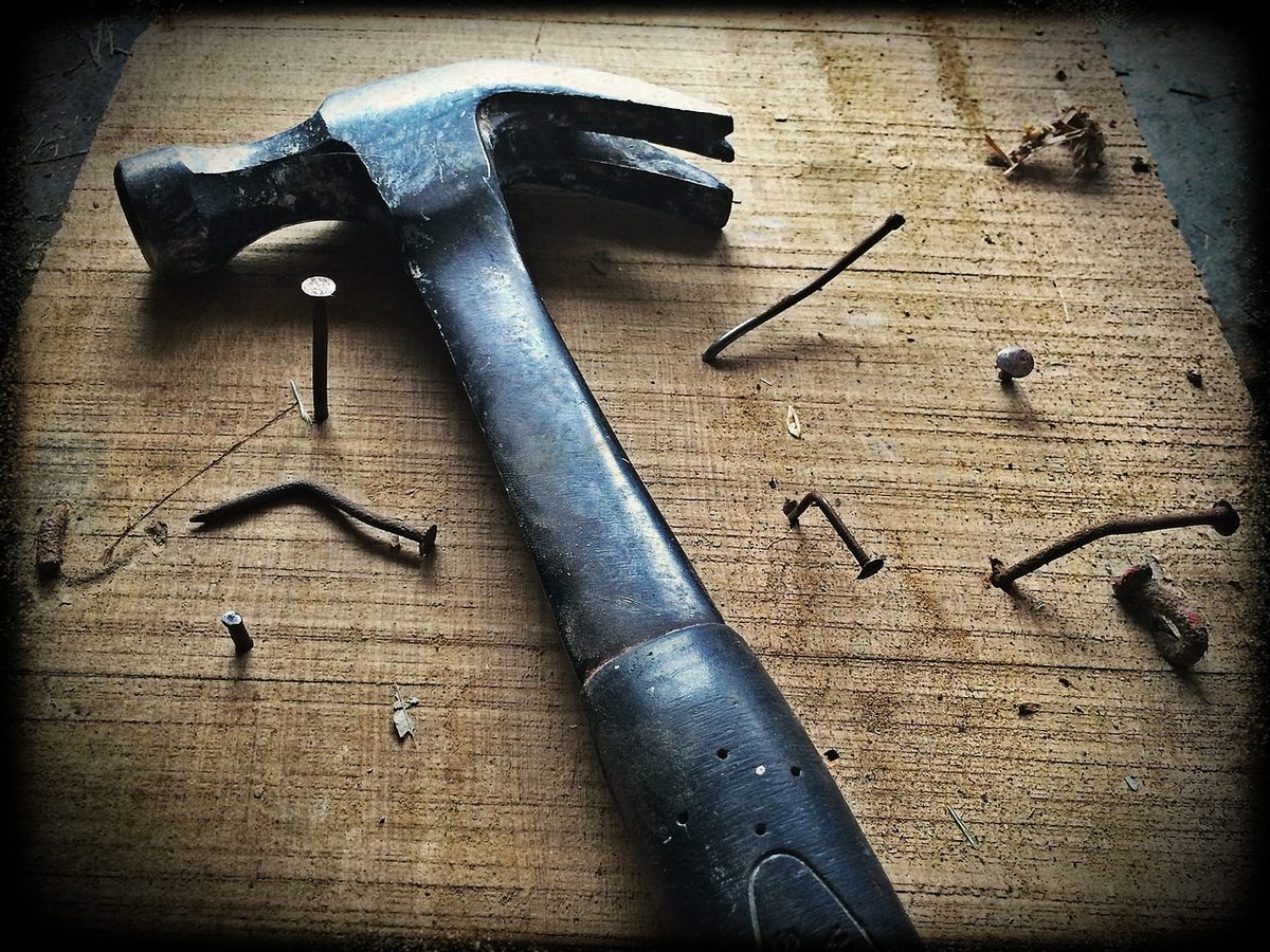 Hammer and bent nails on a wooden board (Florida handyman insurance)