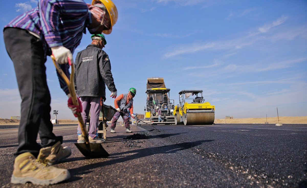 Road crew laying asphalt with a paver and roller (Florida paving contractor insurance)
