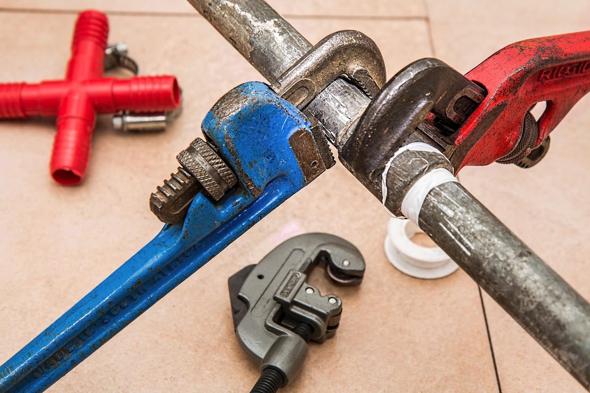 Pipe wrenches and a pipe cutter on a plumbing pipe (Florida plumber insurance)