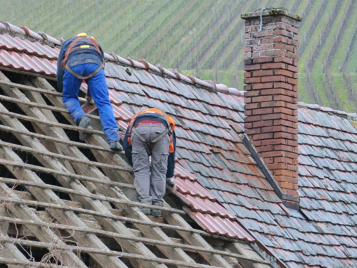 Roofers in safety harnesses working on a tile roof (Florida roofing contractor insurance)