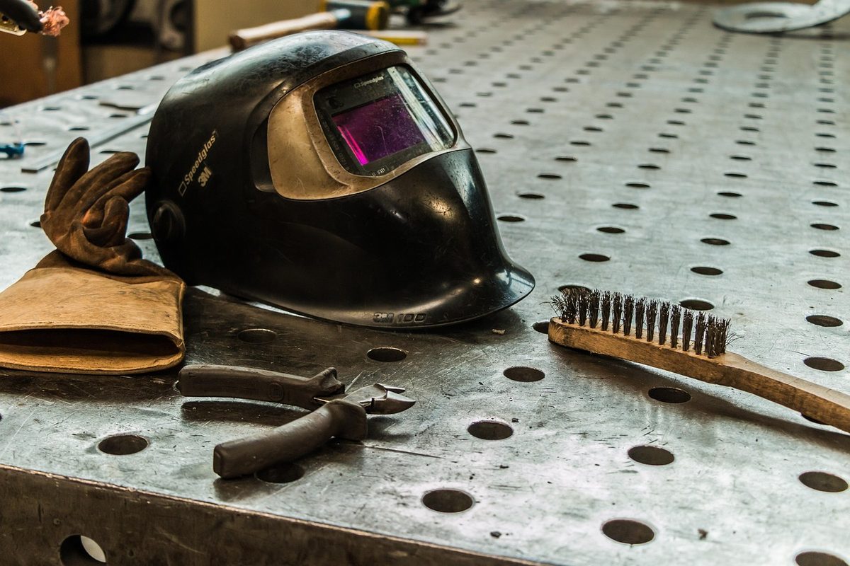 Welding helmet, gloves and wire brush on a welding table (Florida school insurance)