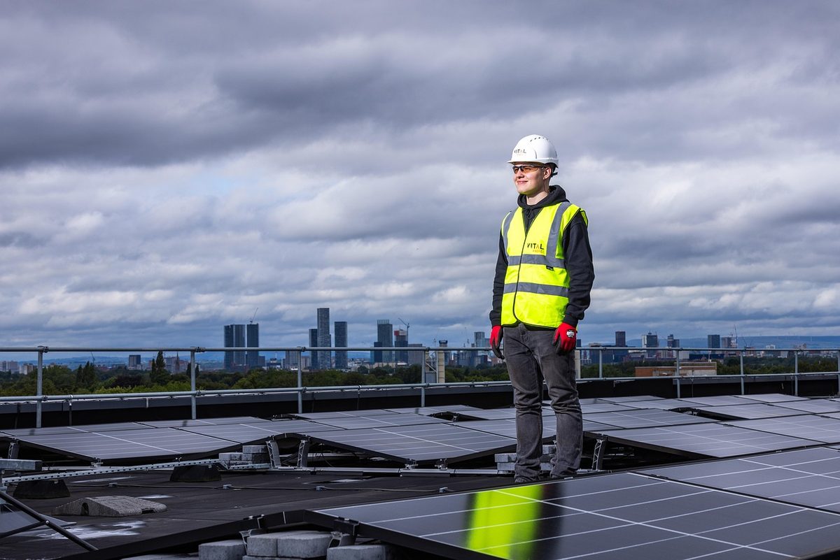 Worker in a hard hat and safety vest on a rooftop (Florida workers compensation insurance)