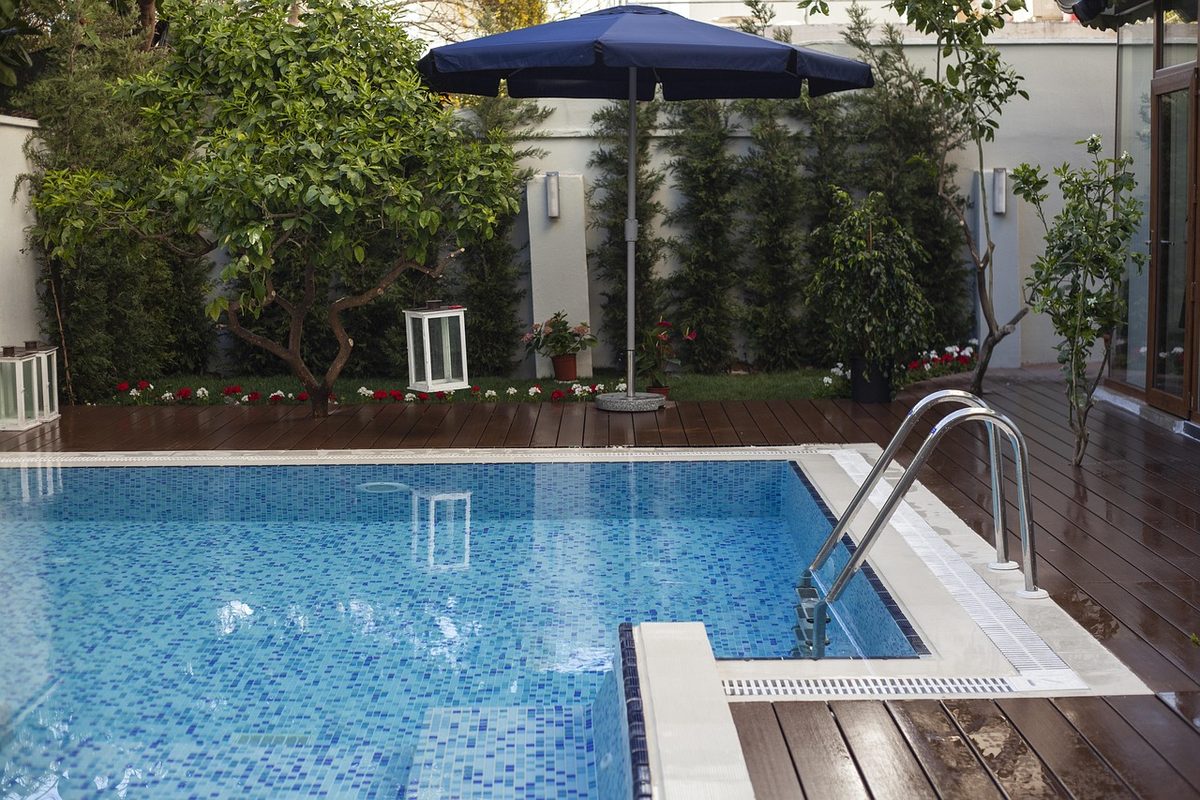 Backyard swimming pool with a ladder and patio umbrella (swimming pool contractor insurance)