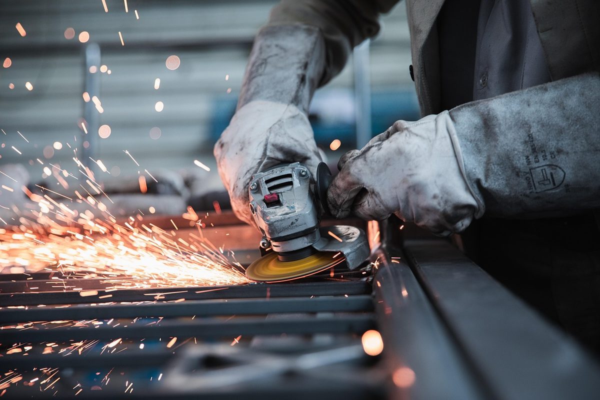 Worker in protective gloves using an angle grinder (Texas workers compensation insurance)