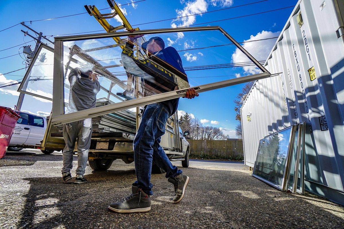 Installers carrying a large window frame (window installers insurance)